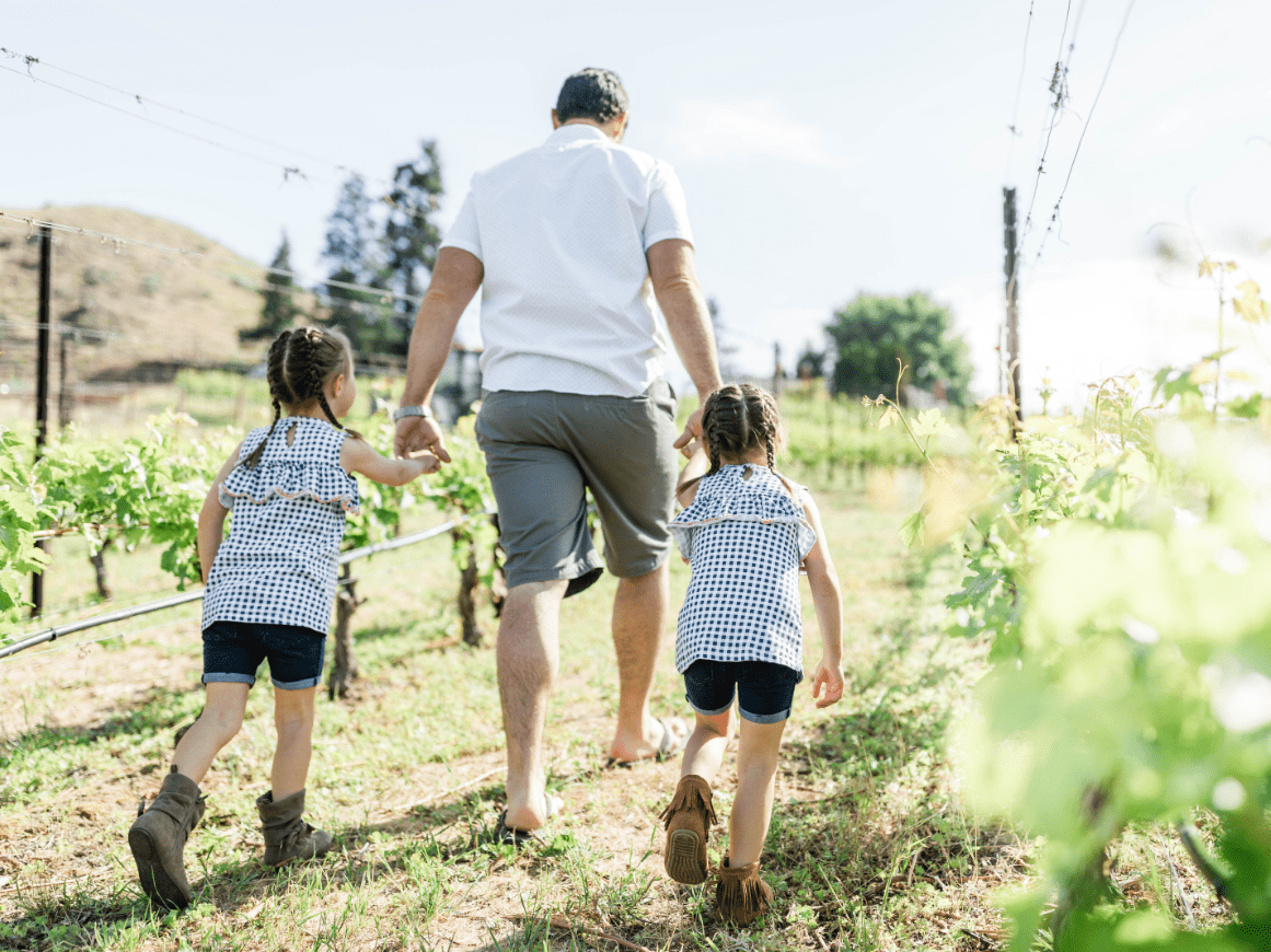 Father and two children walking through a vineyard